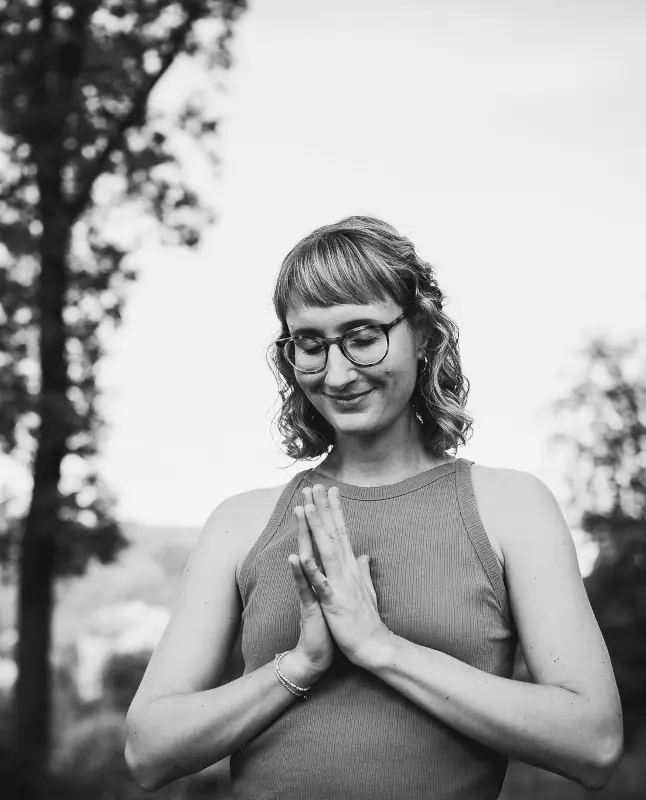 Marie Rohde von vispharana yoga schließt im Park Babelsberg in Potsdam lächelnd die Hände im Mudra vor dem Herzen.