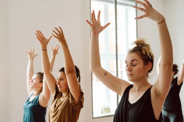 Teilnehmerinnen des Yogacoaching Workshops Selbstwert und Selbstliebe heben zuversichtlich beim Yoga die Arme.