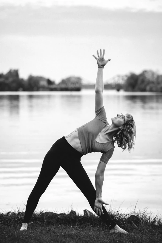 Marie Rohde von vispharana yoga praktiziert mutig und achtsam die Yogaübung Trikonasana im Park Babelsberg in Potsdam.